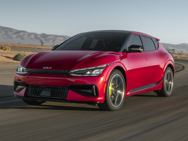 A red Kia driving on the street