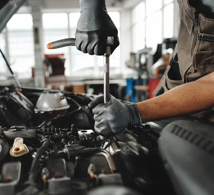 Service technician tightening a part in a vehicle engine bay